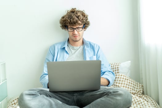 work from home. young caucasian man working on computer laptop. study online listening learning education course conference calling sit laying down on bed elearning concept, freelancer at home photo