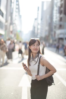 Tokyo tech stroll, Asian woman immersed in her smartphone, blending modern technology with urban lifestyle. photo