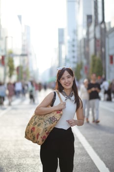 Japanese street vibes, A young Asian woman, confidently standing at road corner, a stylish tote bag adding flair to her casual and trendy urban life. photo