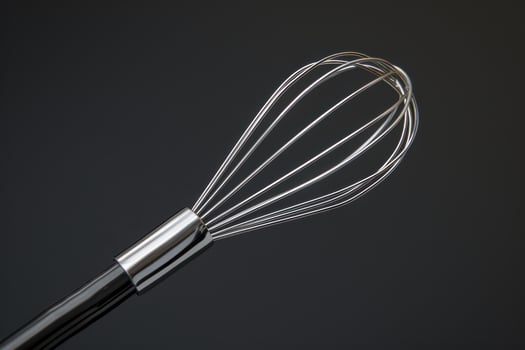 Close-up of a stainless steel whisk against a dark background showcasing its sleek design and functionality in cooking photo