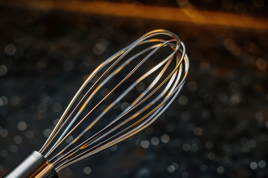 Close-up of a stainless steel whisk against a dark background with soft light reflections photo