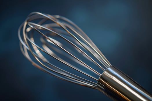 Close-up of a stainless steel whisk on a dark background photo