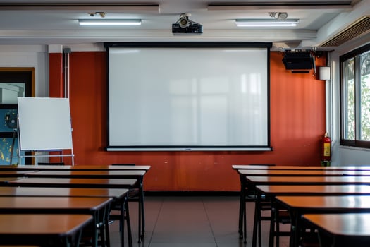 Classroom setting with empty desks and a projector screen in a well-lit learning space photo
