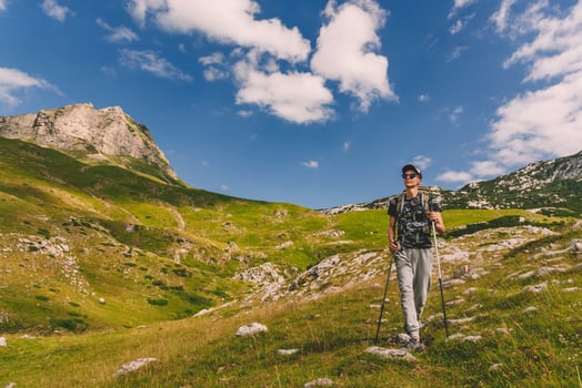 Woman Hiker Walking with Hiking Poles on Mountains photo