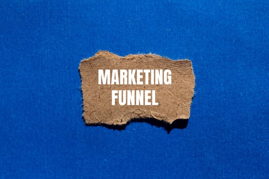 Marketing funnel message written on ripped torn cardboard paper piece on blue background. Conceptual marketing funnel symbol. Copy space. photo