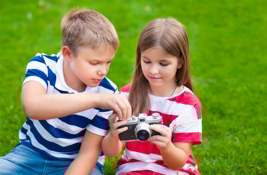 Pretty little brother and sister playing with a camera in summer park photo