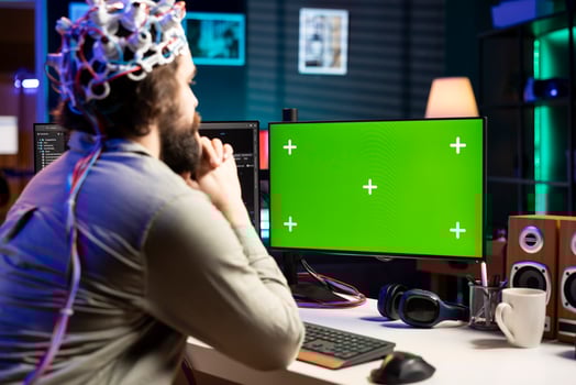 Neuroscientist using EEG headset to upload his mind into green screen computer, attaining immortality. Software developer using mockup PC, experimenting with transferring consciousness into cyberspace photo