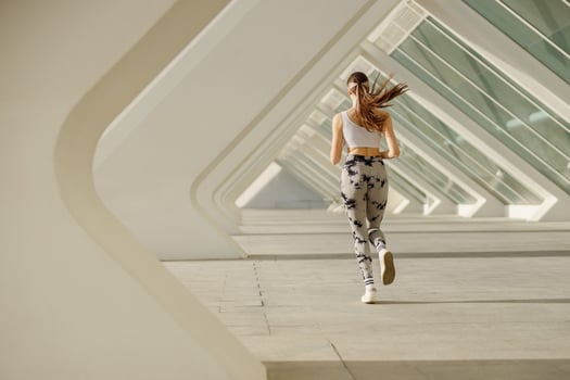 Back view of woman athlete is jogging on morning on modern building background. Healthy life concept photo