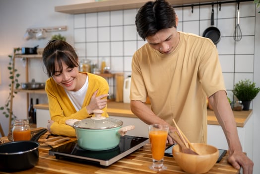 A pretty Asian woman is enjoying cooking with her boyfriend in the kitchen. photo