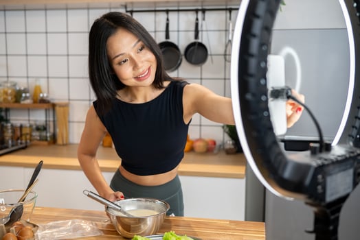 Beautiful Asian female food blogger is recording herself while making a healthy dish in the kitchen. photo