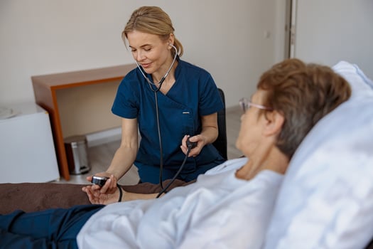 Female nurse checking blood pressure of senior woman in the ward of modern clinic photo