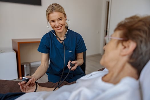 Smiling doctor therapist checking blood pressure of senior woman in the ward of modern clinic photo