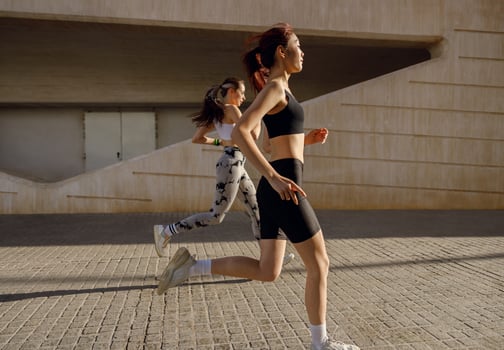 Active female friends athlete are running on sunny morning on modern buildings background photo