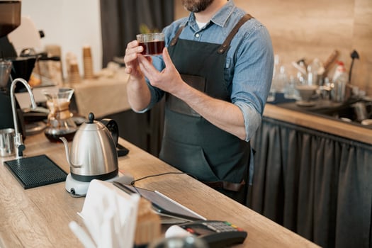 barista holds a glass of fragrant filter coffee in his hands photo