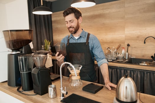 Barista holding a container with coffee beans before installing in the coffee machine photo