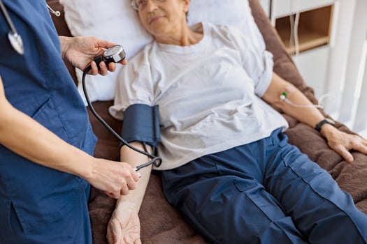 Close up of doctor therapist checking blood pressure of senior woman in the ward of modern clinic photo