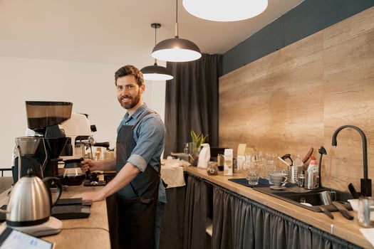 Smiling barista holding glass with filter coffee standing behind the counter photo
