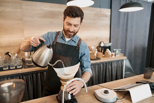 Barista pouring water to make coffee using manual drip brewer photo