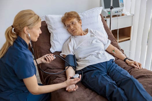 Female doctor therapist checking blood pressure of senior woman in the ward of modern clinic photo