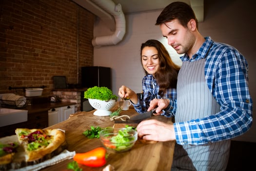 Young man and woman cooking together at kitchen photo