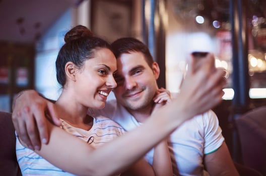 Young woman taking a photo with her mobile phone in a cafe