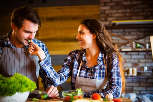Young man and woman cooking and eating together at kitchen photo