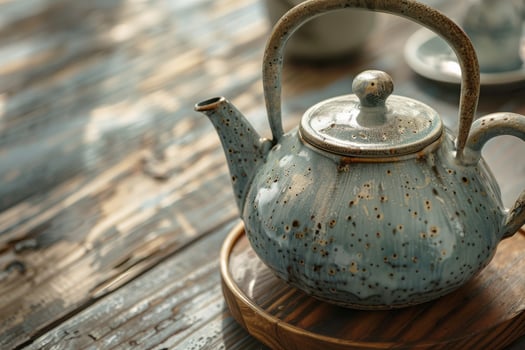 Elegant blue ceramic teapot resting on a wooden table with antique cups nearby photo