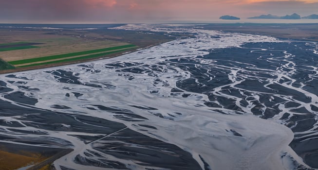 Stunning aerial view of a white water river winding through a dark volcanic landscape in Iceland. Captures the unique beauty of the Icelandic wilderness. photo