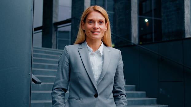 Dreamy business lady standing near office building looking to side confident businesswoman professional manager leader banker turns to camera young smiling successful caucasian woman posing outdoors photo
