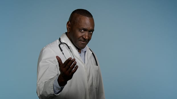 African american man in medical gown walking in gray background studio male doctor hospital employee invites patients to use professional service medicare waving hand makes come here beckoning gesture photo