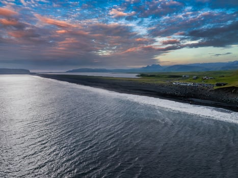 Aerial View of Black Sand Beach with Green Hills and Colorful Sky in Iceland photo