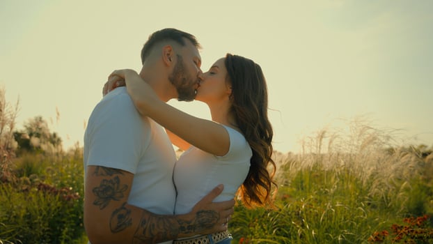 Happy romantic loving Caucasian couple man woman tender family wife husband kiss guy hug girl showing love hugging embracing kissing outdoors deserted wheat field sunrise sunshine dating relationship photo