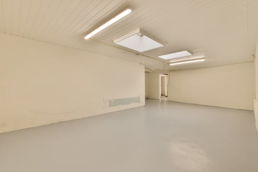An empty room with a skylight and a ceiling fan photo