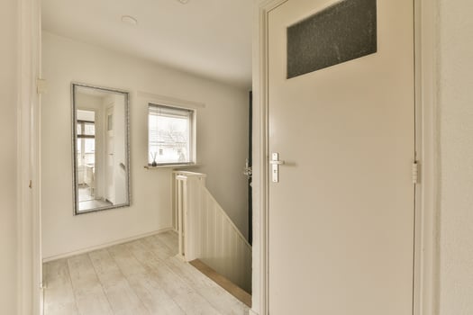 A hallway with a mirror and a door photo