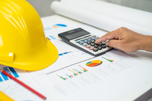 Asian engineer with architectural house plan project blueprint, graph and yellow helmet and engineering construction tools. photo