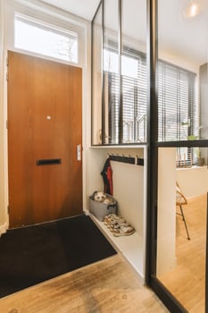 A modern entryway with a wooden door and a black rug photo