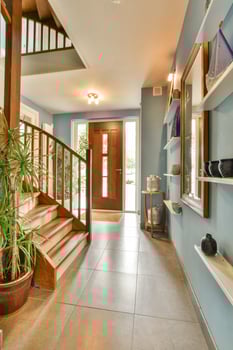 A hallway with a staircase and a plant photo