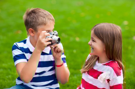 Pretty little brother and sister playing with a camera in summer park photo