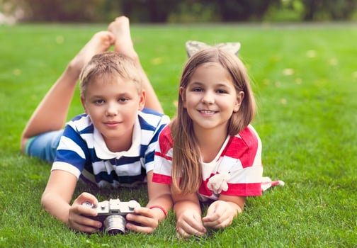 Pretty little brother and sister playing with a camera in summer park photo