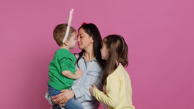 Adorable lovely family showing love and laughing on camera, children feeling happy and playful in studio. Mother with a boy and a girl kissing and hugging each other, joyful people. Camera A. photo