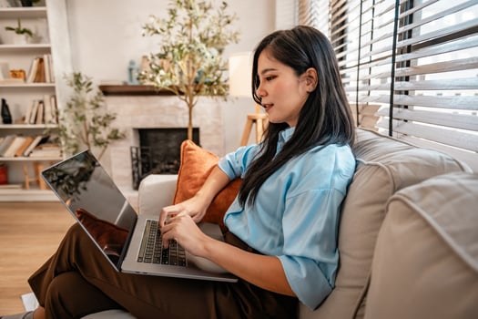 woman is sitting on a couch with a laptop in front of her photo