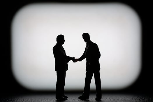 Miniature businessman in a professional agreement, with a blurred background to emphasize the interaction. photo