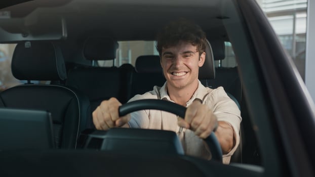 Happy Caucasian man driving new luxury electric crossover car in automobile salon dealership rejoice buy celebrate sitting inside cab auto transport credit loan emotions of happiness buyer achieve photo