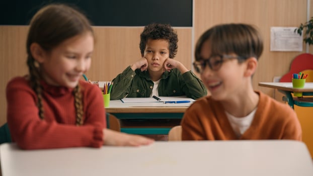 Two Caucasian children school lesson girl boy classmates laughing talk evil laugh mocking bully African American kid child schoolboy sad upset stressed lonely mock bullying kids class discrimination photo