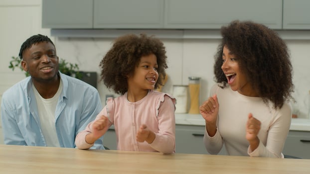 Carefree African American family biracial ethnic happy parents and cute little child girl kid dancing to music having fun together in kitchen at home funny mother father with daughter enjoying dance photo