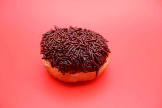 donut with chocolate sprinkle isolated on red background photo