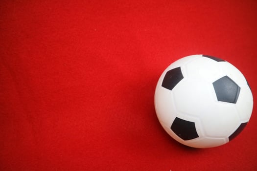 a small white and black toy rubber ball. Red background photo