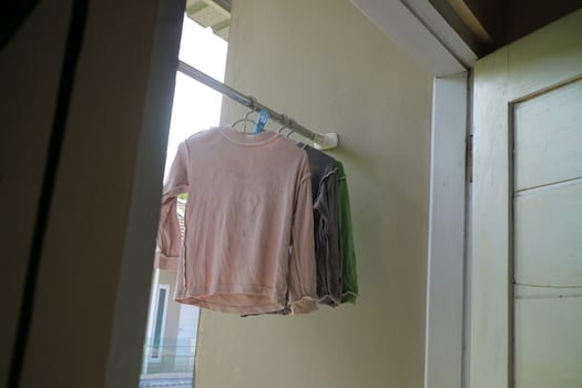 Several long sleeve children's t-shirts are drying on the balcony of the house during the day photo