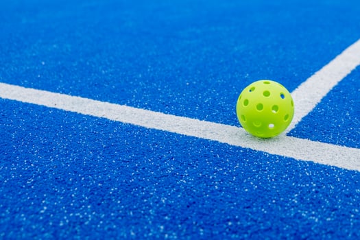Isolated green pickleball ball in a court, new racket sport photo