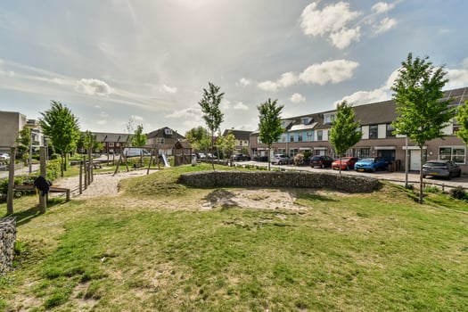 A view of a park with a grassy area and a house photo